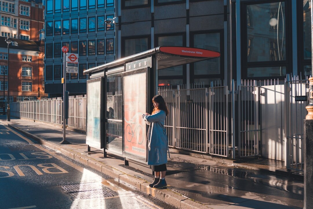 Danish woman waiting at a bus stop reading a newspaper