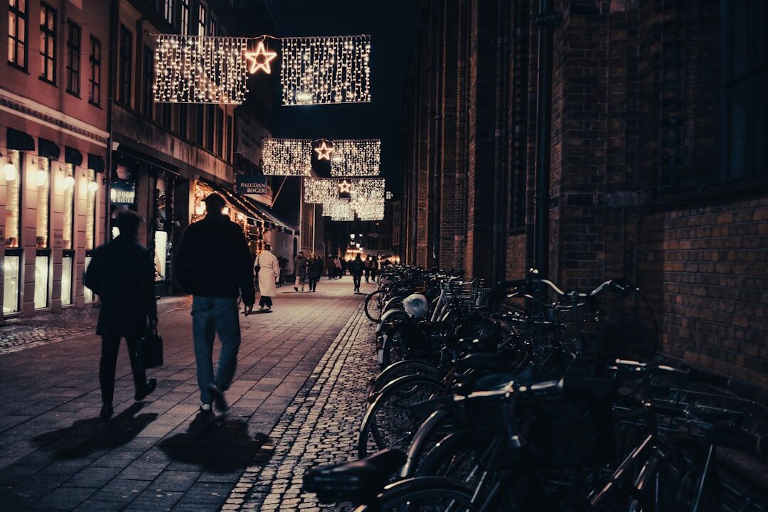 Cyclists riding through a cobblestone street in central Copenhagen at dusk
